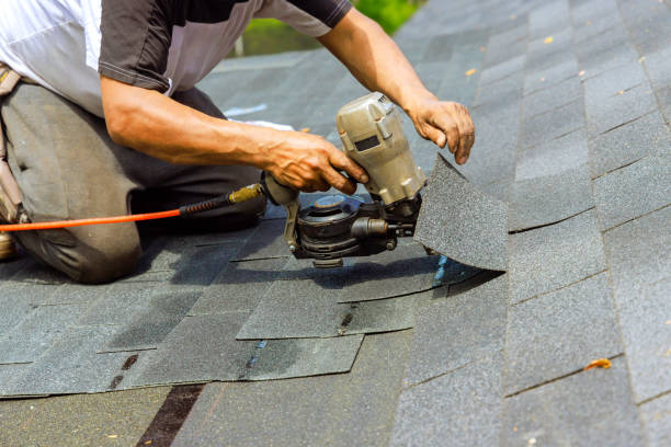 Professional roofer repairing damaged asphalt shingles on a residential roof in Cincinnati Ohio